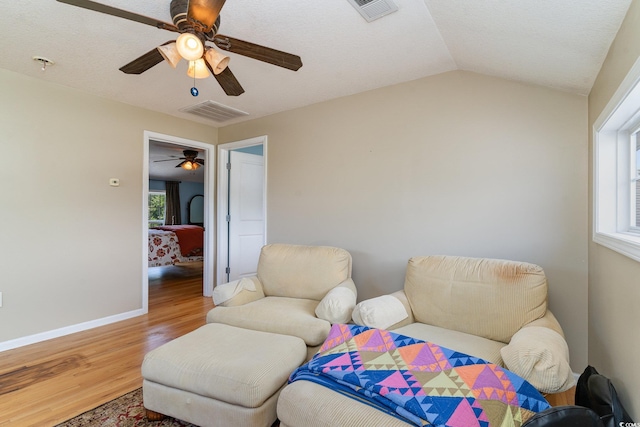 sitting room with ceiling fan, lofted ceiling, wood-type flooring, and a wealth of natural light