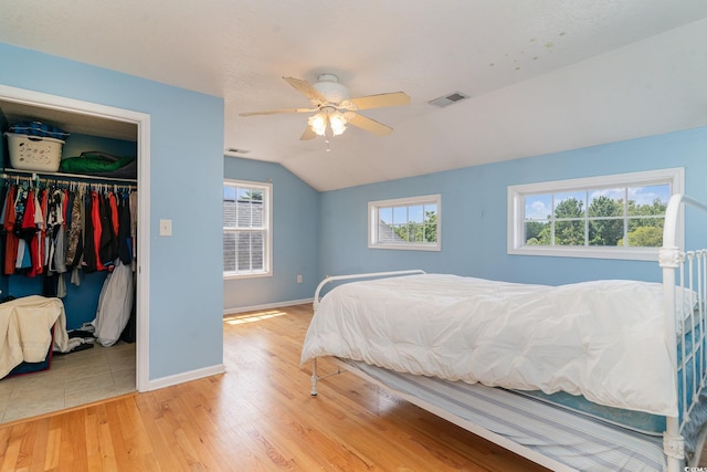 bedroom featuring lofted ceiling, light hardwood / wood-style floors, a closet, and ceiling fan