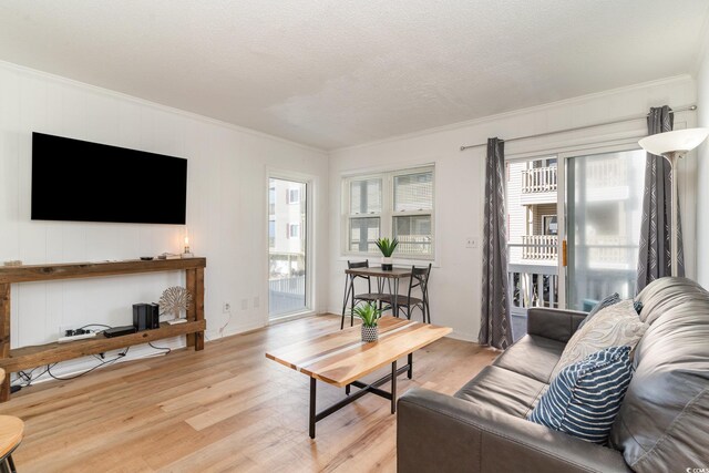 living room featuring crown molding, a textured ceiling, and light hardwood / wood-style floors