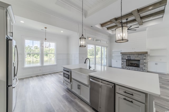 kitchen with appliances with stainless steel finishes, sink, pendant lighting, a center island with sink, and gray cabinets