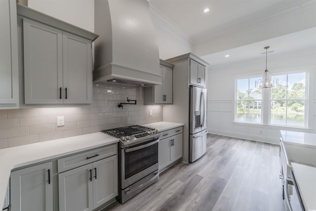 kitchen with premium range hood, stainless steel appliances, an inviting chandelier, light hardwood / wood-style flooring, and gray cabinets