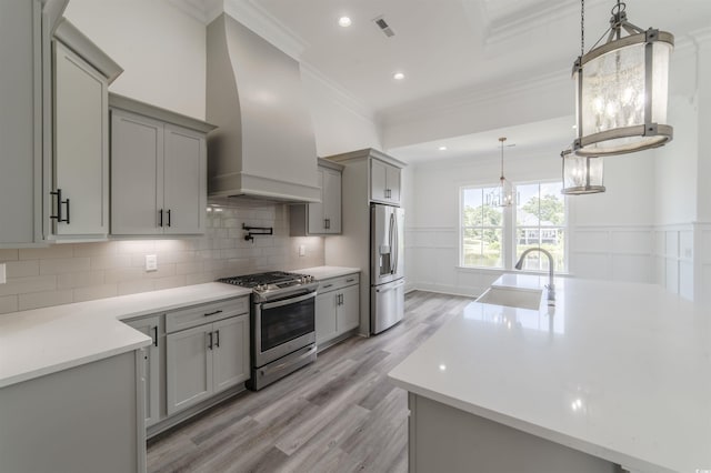 kitchen with crown molding, sink, light wood-type flooring, appliances with stainless steel finishes, and custom range hood