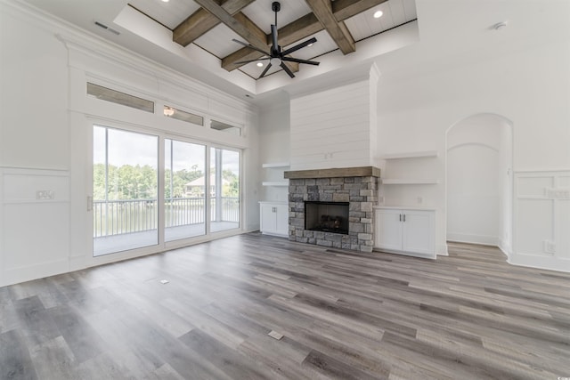 unfurnished living room featuring a high ceiling, a fireplace, light hardwood / wood-style floors, and coffered ceiling