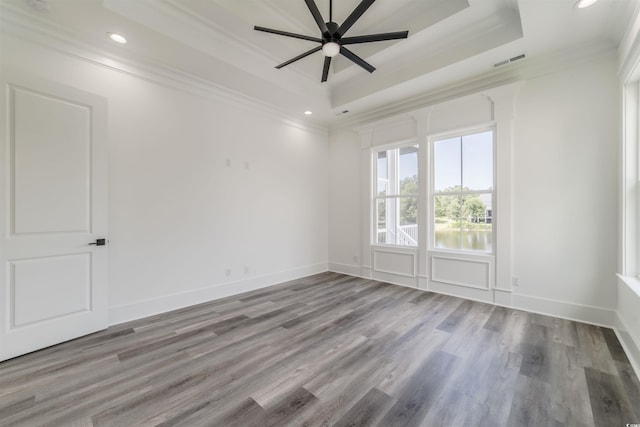 empty room featuring hardwood / wood-style floors, ceiling fan, a raised ceiling, and ornamental molding