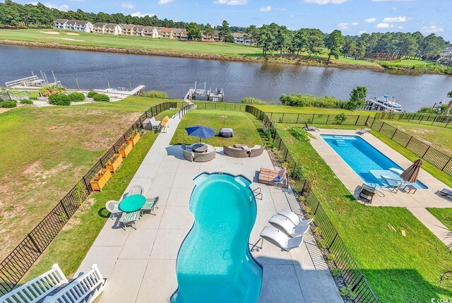 view of pool with a water view, a patio area, and a lawn