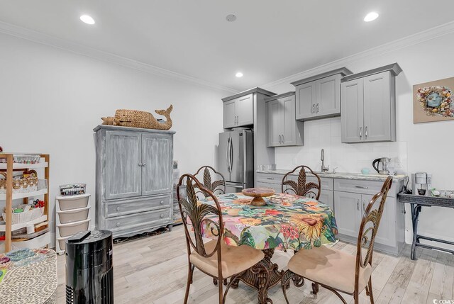 dining room with ornamental molding and light hardwood / wood-style floors