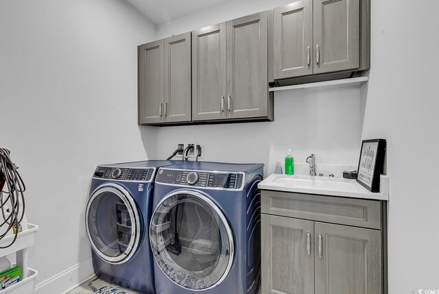 laundry room with cabinets, washing machine and clothes dryer, and sink