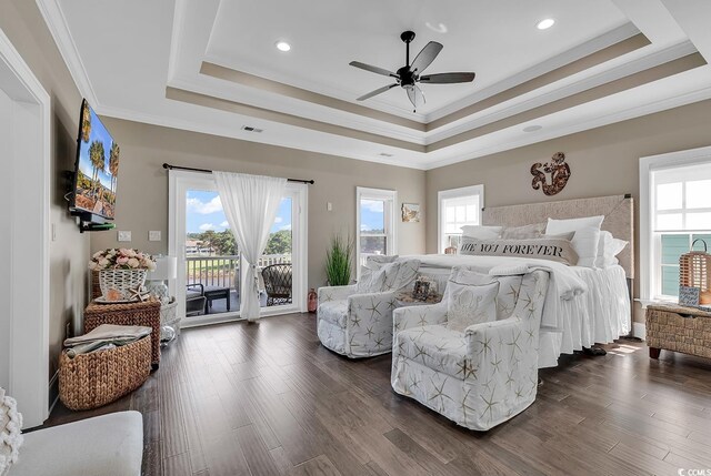 bedroom featuring dark hardwood / wood-style floors, a tray ceiling, multiple windows, and access to outside