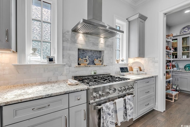 kitchen featuring a healthy amount of sunlight, wall chimney range hood, high end stainless steel range, and light stone counters