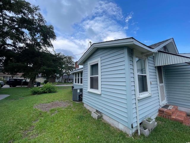 view of home's exterior with a lawn and central AC unit