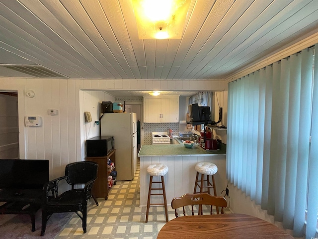 kitchen featuring white appliances, kitchen peninsula, and a breakfast bar