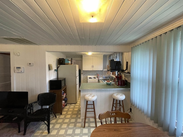 kitchen featuring visible vents, light countertops, a peninsula, light floors, and white appliances
