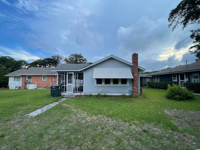 rear view of property featuring a lawn and cooling unit