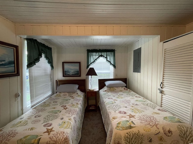 carpeted bedroom with electric panel and wood walls