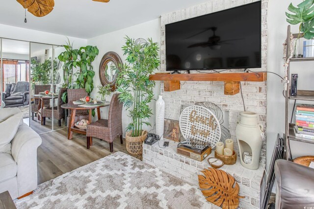 living room with ceiling fan, a fireplace, and light hardwood / wood-style floors