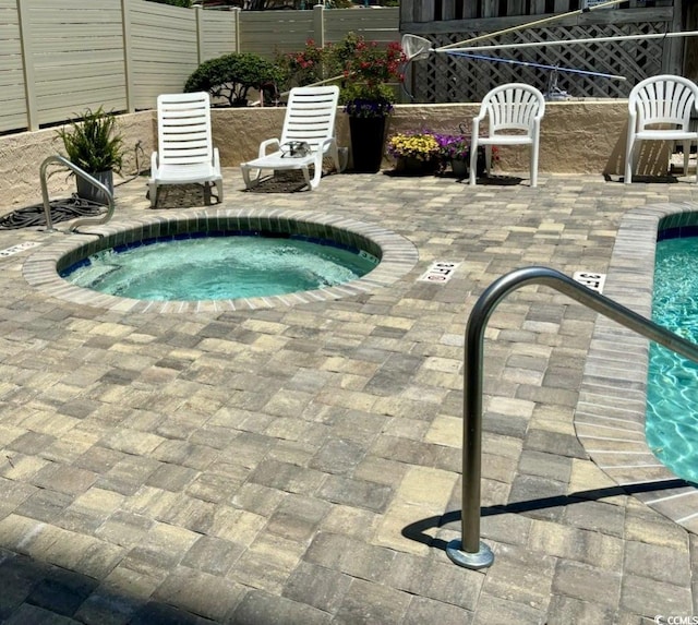 view of pool with a hot tub and a patio area