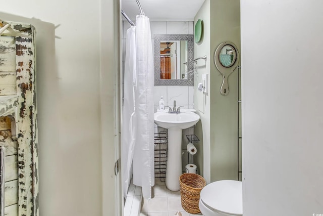 bathroom with tile patterned floors, walk in shower, sink, tile walls, and toilet