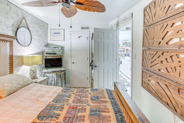 bedroom featuring ceiling fan and brick wall