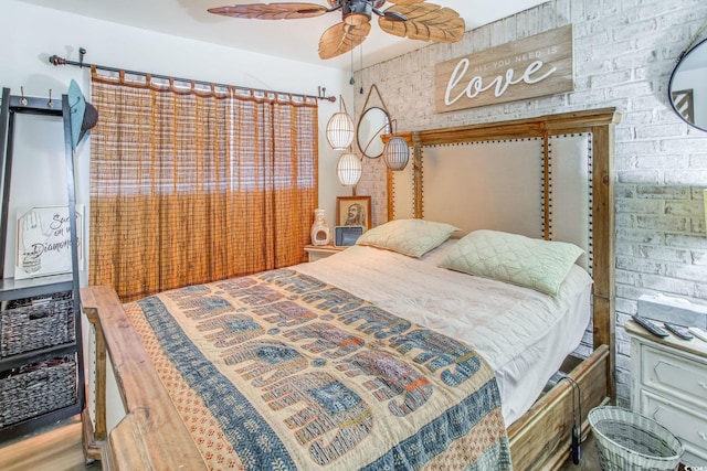 bedroom featuring hardwood / wood-style floors, ceiling fan, and brick wall