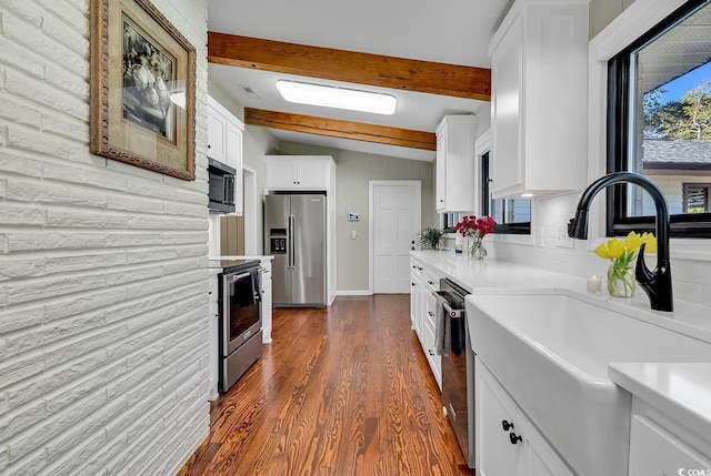 kitchen with dark wood-type flooring, sink, white cabinets, appliances with stainless steel finishes, and vaulted ceiling with beams