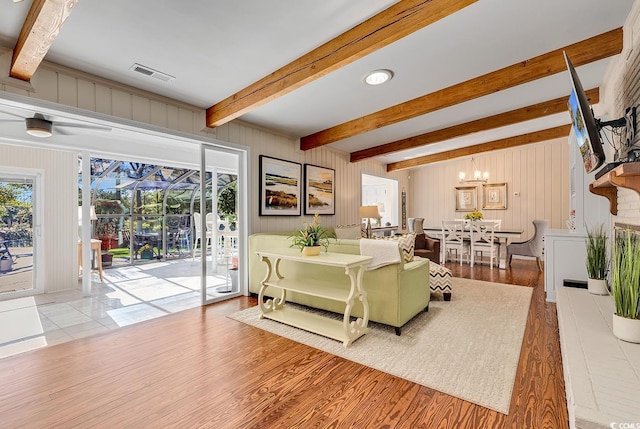 living room featuring beam ceiling, light hardwood / wood-style flooring, and an inviting chandelier