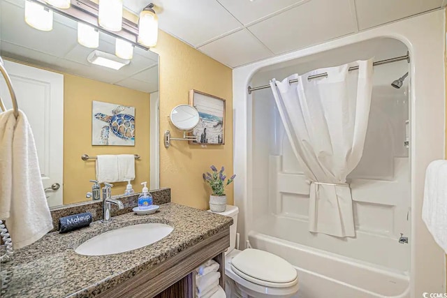 full bathroom with shower / bathtub combination with curtain, a drop ceiling, vanity, and toilet