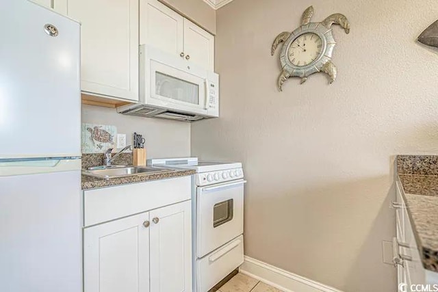 kitchen with light tile patterned flooring, white cabinets, white appliances, and sink