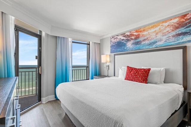 bedroom featuring ornamental molding, a water view, and hardwood / wood-style floors