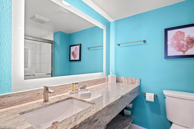 bathroom featuring vanity, a shower with shower door, and toilet