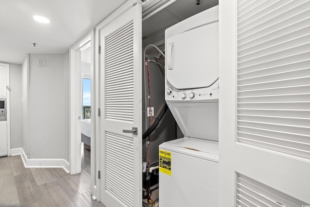 clothes washing area featuring light hardwood / wood-style flooring and stacked washer / dryer