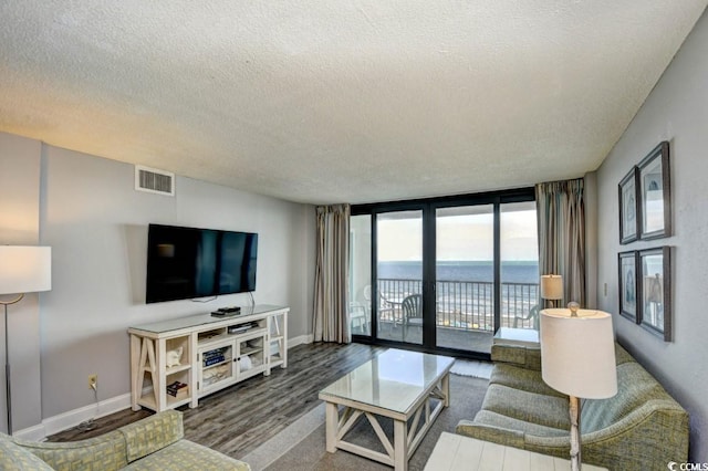 living room with floor to ceiling windows, dark hardwood / wood-style floors, and a textured ceiling