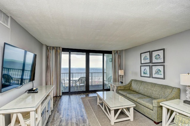 living room with hardwood / wood-style flooring, expansive windows, a textured ceiling, and a water view