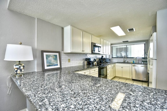 kitchen featuring appliances with stainless steel finishes, kitchen peninsula, sink, and dark stone counters