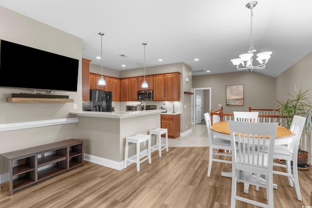 kitchen with hanging light fixtures, black fridge with ice dispenser, a chandelier, and light hardwood / wood-style floors