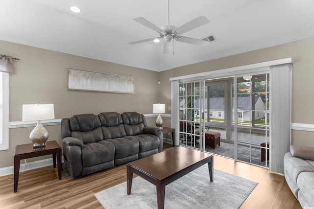 living room featuring ceiling fan, light hardwood / wood-style floors, and vaulted ceiling