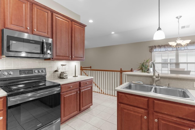 kitchen featuring hanging light fixtures, light tile patterned floors, stainless steel appliances, sink, and decorative backsplash