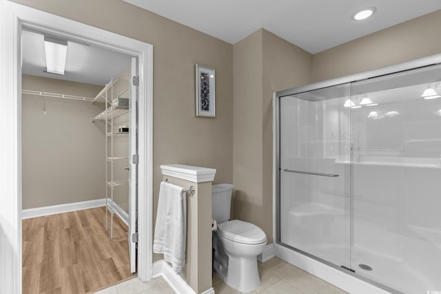 bathroom featuring toilet, wood-type flooring, and an enclosed shower