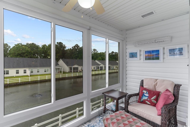 sunroom / solarium featuring a water view and ceiling fan