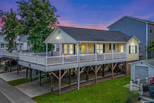 back house at dusk featuring a porch and a storage unit