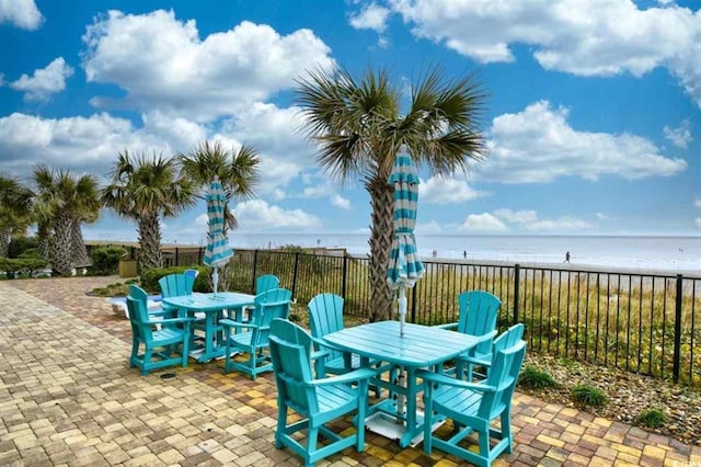 view of patio with a water view and a beach view