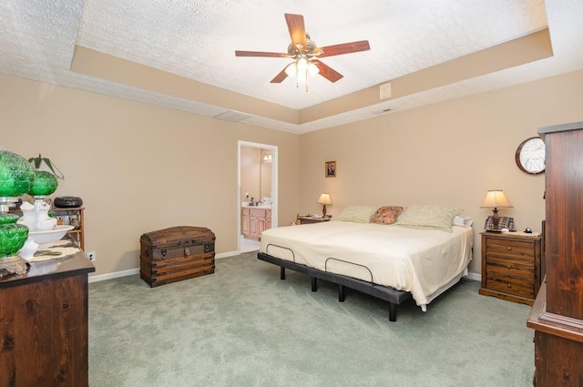 carpeted bedroom with ceiling fan, ensuite bath, a tray ceiling, and a textured ceiling