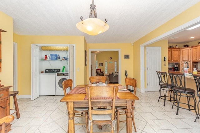 tiled dining area with sink, washing machine and dryer, and a textured ceiling