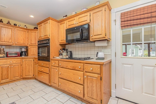 kitchen with light tile patterned floors, backsplash, and black appliances