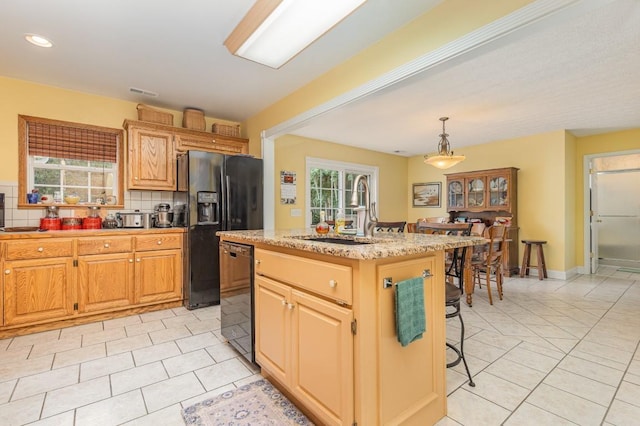 kitchen with pendant lighting, tasteful backsplash, sink, a center island, and black appliances