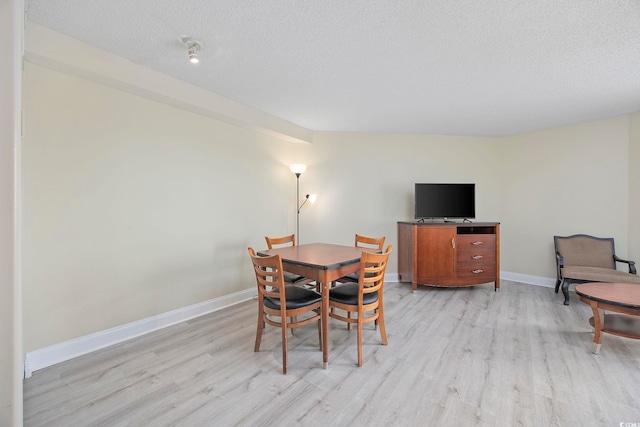 201 S Ocean Blvd Unit 1005, Myrtle Beach, SC 29577 - dining space with light wood-style floors, a textured ceiling, and baseboards