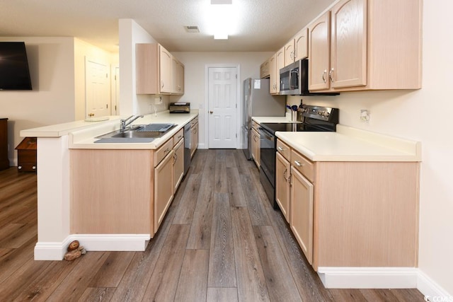 kitchen with appliances with stainless steel finishes, light countertops, a peninsula, and light brown cabinets