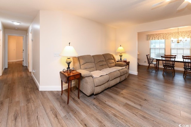 living room with wood-type flooring and ceiling fan with notable chandelier