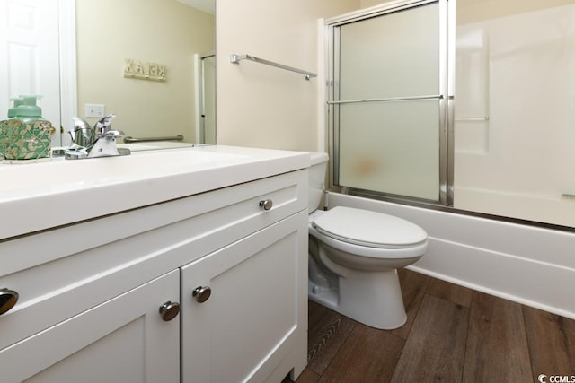 full bathroom featuring shower / bath combination with glass door, vanity, hardwood / wood-style flooring, and toilet