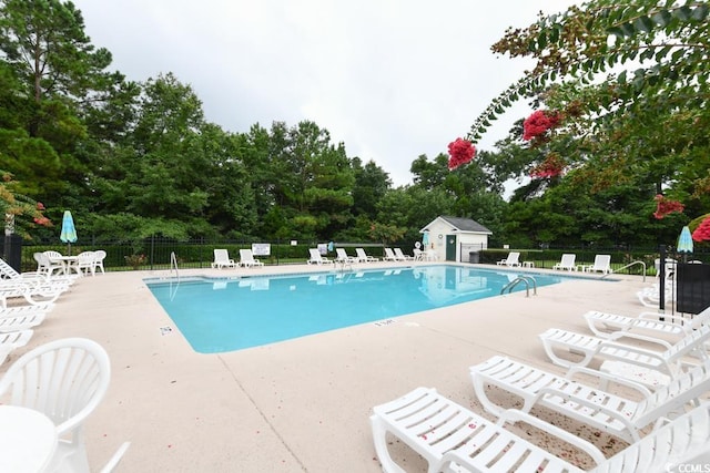 view of swimming pool with a patio and an outbuilding