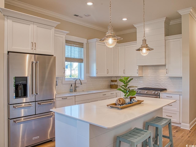 kitchen featuring decorative backsplash, sink, light wood-type flooring, a kitchen island, and high end appliances